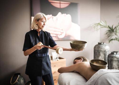 a woman is holding two bowls over a man at Hotel Angelo Engel in Ortisei