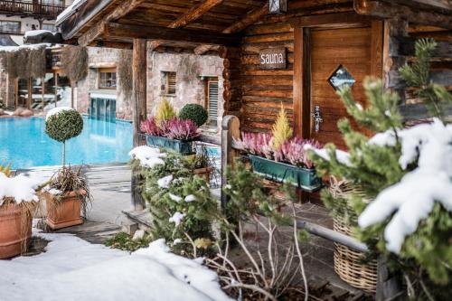 a log cabin in the snow with a swimming pool at Hotel Angelo Engel in Ortisei