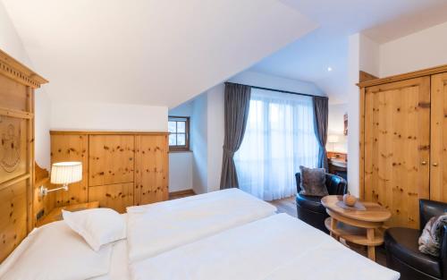 a bedroom with a bed and a chair and a window at Hotel Angelo Engel in Ortisei