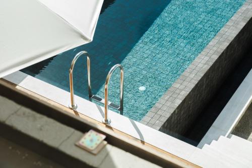 een zwembad met drie metalen handvatten naast een zwembad bij Greenvale Park Villas in Paphos