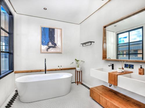 a bathroom with a large white tub and a sink at Secana Beachtown in Canggu
