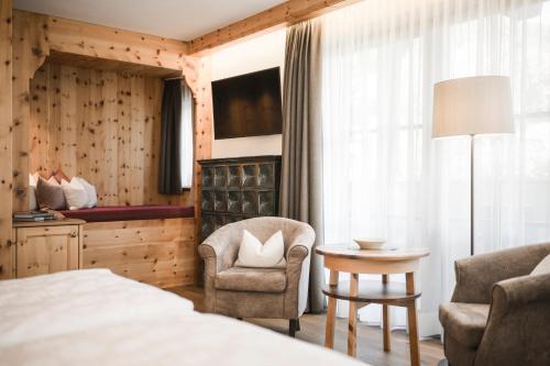 a bedroom with a bed and a chair and a table at Hotel Angelo Engel in Ortisei