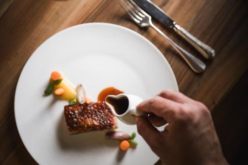 a person is drinking from a cup on a plate of food at Hotel Angelo Engel in Ortisei