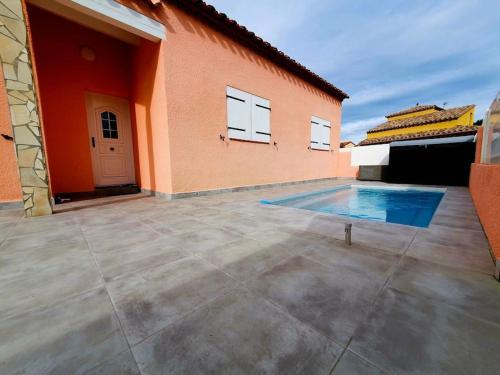 une maison avec une piscine à côté d'un bâtiment dans l'établissement Villa H2o - Jacuzzi & Piscine, au Barcarès