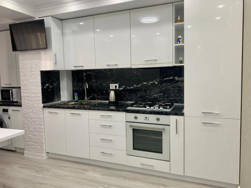 een keuken met witte kasten en zwarte aanrechtbladen bij Comfortable apartments!!! View!!! in Chişinău