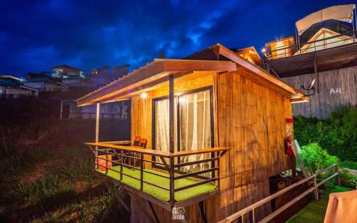una piccola cabina in legno con balcone su una casa di อาฉ่างแคมป์ Achang Camp a Mon Jam