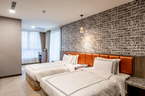 two beds in a room with a brick wall at San Chiao Hotel in Daxi