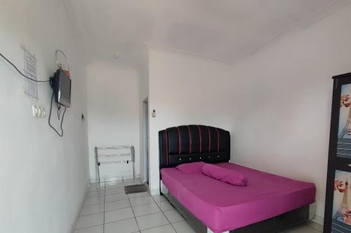 Un pequeño dormitorio con una cama rosa en una habitación en OYO 93252 Garuda Bandara Guesthouse, en Palembang