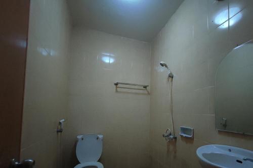 W łazience znajduje się toaleta, umywalka i lustro. w obiekcie OYO 93252 Garuda Bandara Guesthouse w mieście Palembang