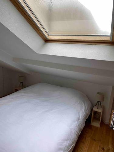 a bedroom with a white bed and a window at T2 duplex4 Hyper-centre climatisé in Albi
