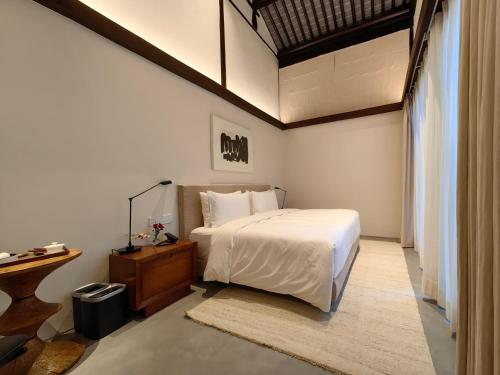 sypialnia z białym łóżkiem i drewnianym stołem w obiekcie Jiangnan House Changyuan w mieście Suzhou