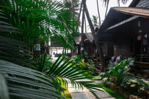 a garden with palm trees and a house at O3 Beach Resort in Palolem