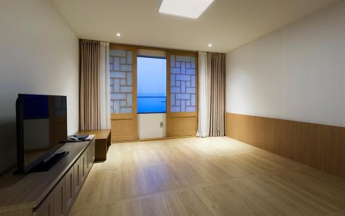 a living room with a television and a large window at Noblepia Hotel in Seogwipo