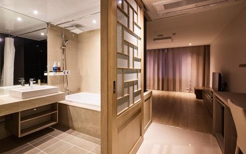 W łazience znajduje się umywalka i wanna. w obiekcie Noblepia Hotel w mieście Seogwipo