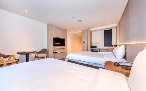 a hotel room with two beds and a television at Noblepia Hotel in Seogwipo