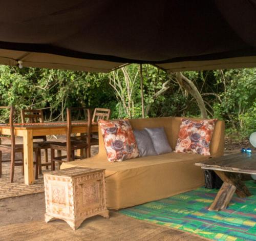 a couch under a tent with a table at Nje Bush Camp in Kwangwazi