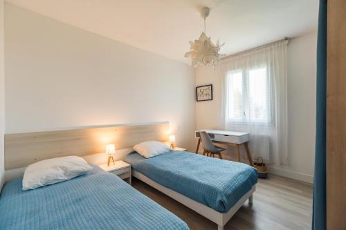 une chambre avec deux lits et un bureau et une fenêtre dans l'établissement Maison Poulpry - Grande maison pour 9 à 600m de la plage, à Penvénan