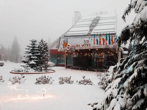 a snow covered building with a store in front of it at Hotel Piatra Mare in Poiana Brasov