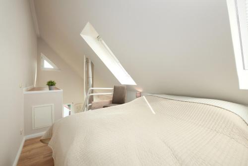 een witte slaapkamer met een bed en een stoel bij Haus Windjammer Windjammer Danmark in Laboe