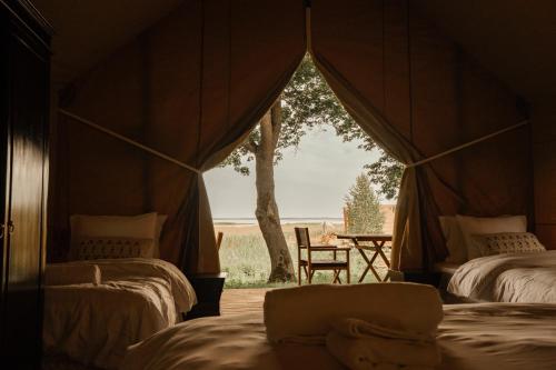Orissaare的住宿－Mia Glamping，帐篷配有两张床、一张桌子和一棵树