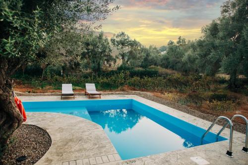 a swimming pool with two lounge chairs next to it at Villa di Vino in Lefkada Town