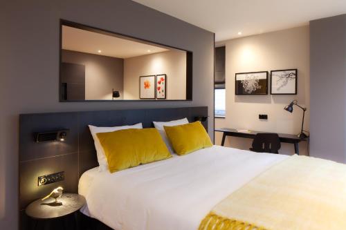 a bedroom with a large bed with yellow pillows and a mirror at Golden Tulip Leiden Centre in Leiden