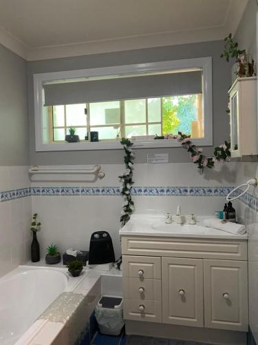 een badkamer met een bad, een wastafel en een raam bij Rocky Rest in Orange