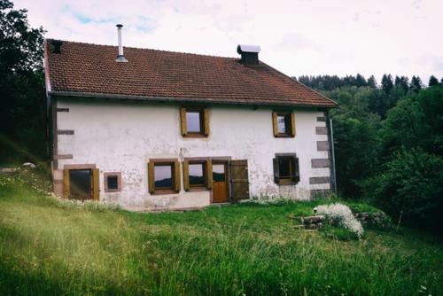 una pequeña casa blanca en un campo de hierba en Bouvacôte La Forcenée, en Le Tholy