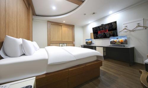 a bedroom with a large white bed and a desk at Hotel Feel Green in Goyang