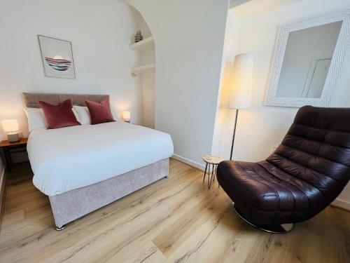 a bedroom with a bed and a leather chair at Liverpool Peach House - 4 bedrooms in Liverpool