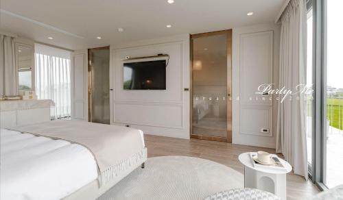 a bedroom with a white bed and a tv on the wall at Party Me 派對蜜民宿 in Dongshan