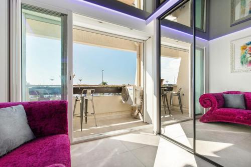 d'un salon avec des meubles violets et de grandes fenêtres. dans l'établissement Lux'art Port Nature, au Cap d'Agde