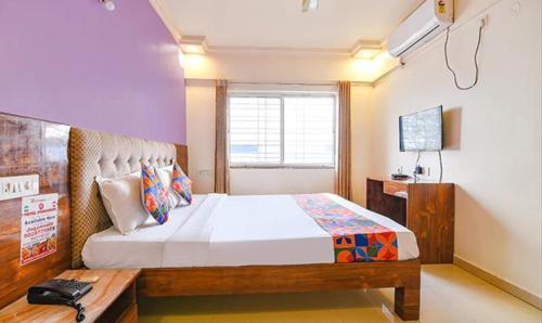 a bedroom with a large bed and a television at FabExpress Kohinoor Residency in Pune