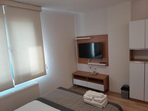 Cette petite chambre blanche dispose d'une télévision et d'un lit. dans l'établissement Del Puerto Hotel, à Aliağa