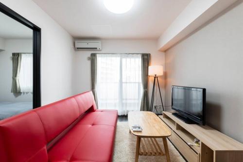 a living room with a red couch and a tv at STELLAR in Ōdōri