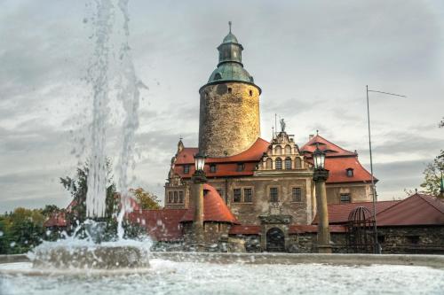 a fountain in front of a building with a tower at Zamek Czocha in Leśna