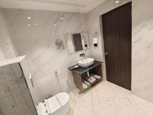 Baño blanco con lavabo y aseo en The Emerald Hotel & Siya Milan Banquets en Muzaffarpur