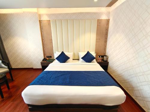 a bedroom with a large bed with blue pillows at The Emerald Hotel & Siya Milan Banquets in Muzaffarpur