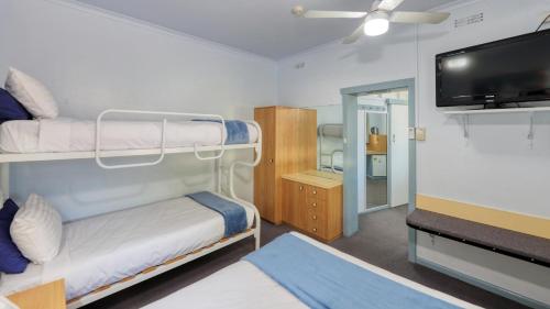 a room with two bunk beds and a flat screen tv at Tumut Farrington motel in Tumut