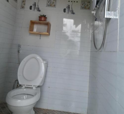 een witte badkamer met een toilet en een douche bij Homestay niem t'rị Măng Pên in Kon Von Kla