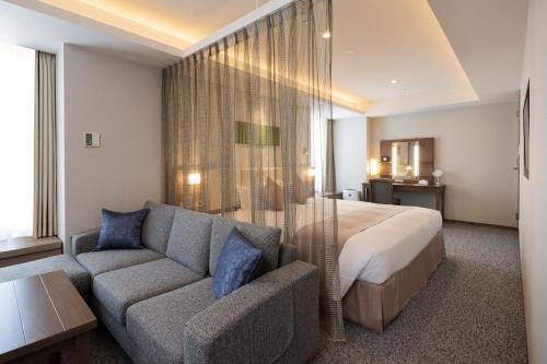 um quarto de hotel com uma cama e um sofá em Sapporo Grand Hotel em Sapporo