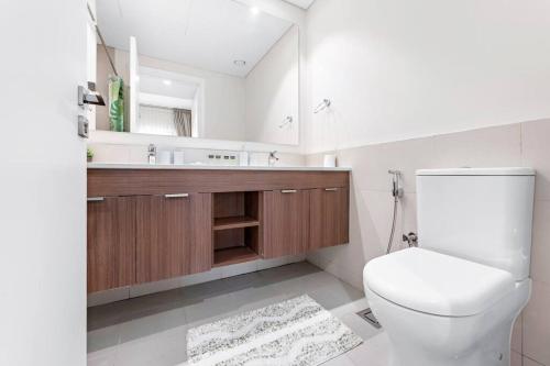 a bathroom with a toilet and a sink and a mirror at StoneTree - Spacious 2BR Apartment in Golf Views Block A in Dubai