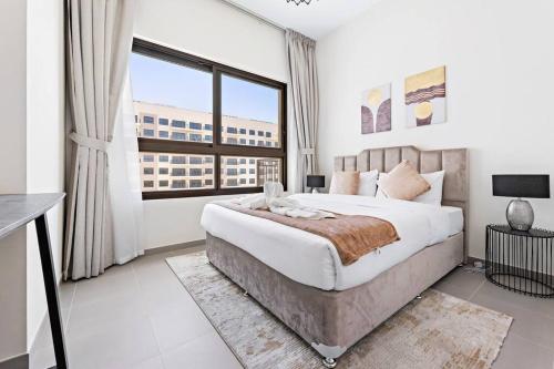 a bedroom with a large bed and a large window at StoneTree - Spacious 2BR Apartment in Golf Views Block A in Dubai