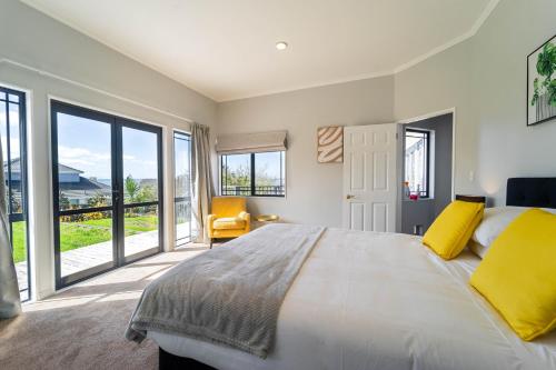 a bedroom with a large bed with yellow pillows at Family Friendly Oceanview Howick Home - Pets+ in Auckland