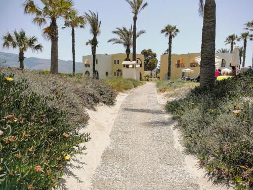 a path to the beach with palm trees and houses at Grecotel Casa Paradiso in Marmari