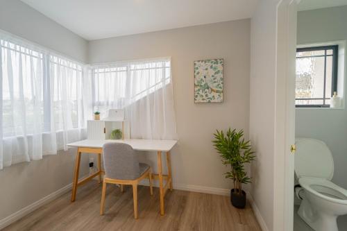 a small bathroom with a desk and a toilet at Family Friendly Oceanview Howick Home - Pets+ in Auckland