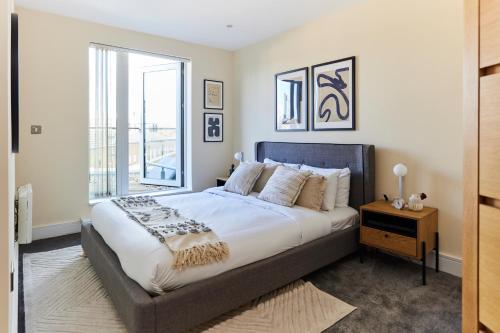 a bedroom with a large bed and a window at The Weavers Field Place - Classy 3BDR Flat with Terrace in London