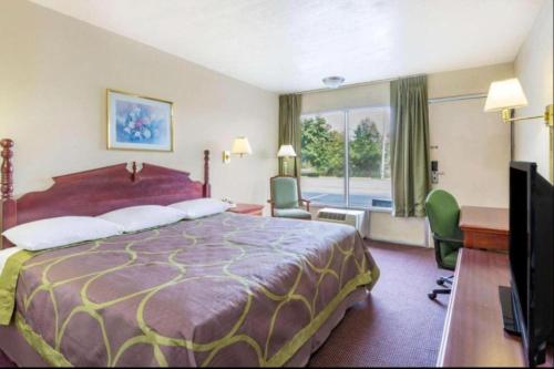 Cette chambre comprend un grand lit et une télévision. dans l'établissement Ashland Studio Inn By OYO Richmond North near Kings Dominion, à Ashland