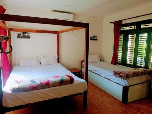 a bedroom with two bunk beds and a window at Tharu Lodge in Sauraha