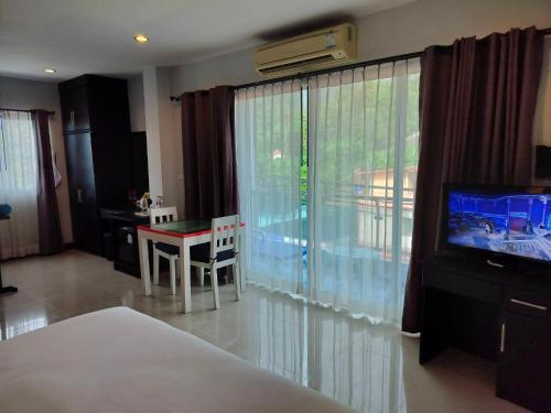 a bedroom with a bed and a television and a table at May House Karon Beach in Karon Beach
